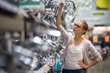 Genç ve güzel kadın bir banyo/mutfak musluk seçimi
