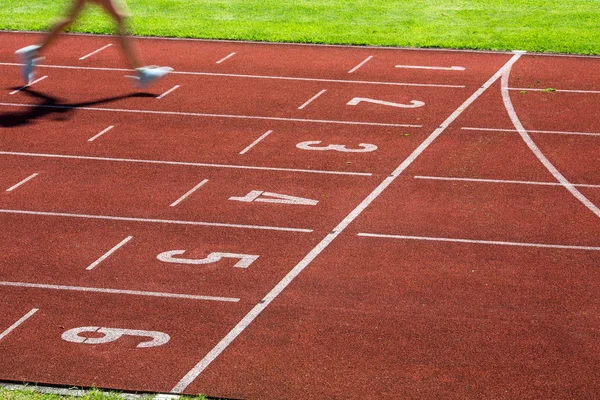 Runner on a running track finishing a race first — Stock Photo, Image