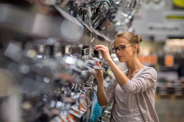 Mooie jonge vrouw die het kiezen van een badkamer/keuken kraan — Stockfoto