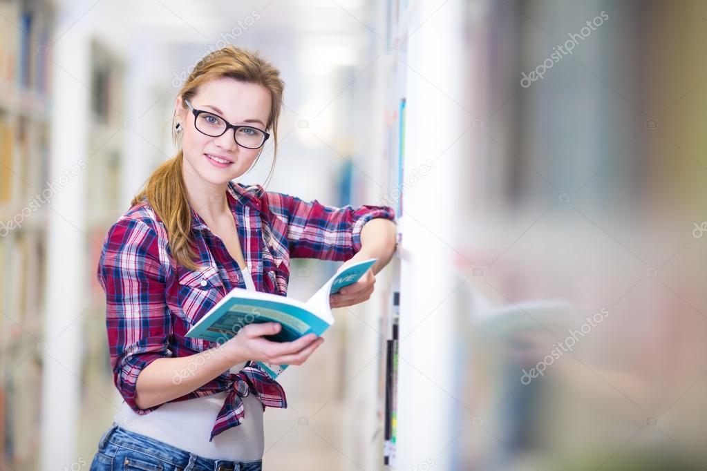 Pretty, female college student in a library, looking for a book 