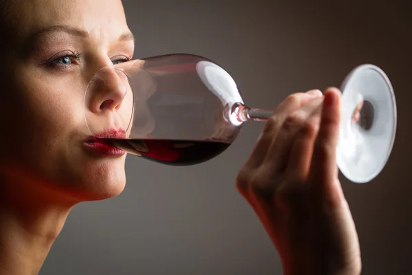Elegáns fiatal nő, egy piros ruhás, miután egy pohár vörös bor — Stock Fotó