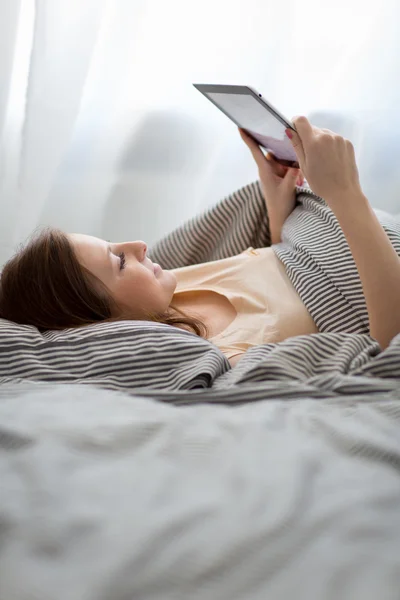 Young woman using her tablet computer in her be — Stock Photo, Image