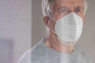 Koronavirüs ve grip salgını sırasında maske takan kıdemli bir adam. Virüs ve hastalık koruması, ev karantinası. COVID-19 kavramı