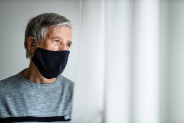 Koronavirüs ve grip salgını sırasında maske takan kıdemli bir adam. Virüs ve hastalık koruması, ev karantinası. COVID-19 kavramı