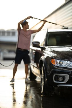 Genç adam herhangi bir hasarı önlemek ve detaylandırmak için sevgili arabasını manuel araba yıkamada dikkatlice yıkıyor.