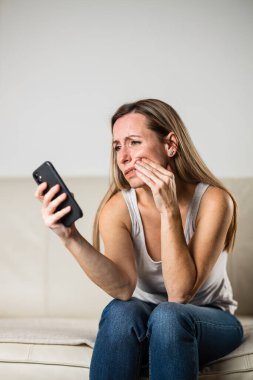 Diş ağrısı / diş sorunu yüzünden orta yaşlı bir kadın acı dolu bir ifadeyle yanağına ve ağzına dokunuyor.