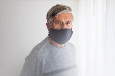 Koronavirüs ve grip salgını sırasında maske takan kıdemli bir adam. Virüs ve hastalık koruması, ev karantinası. COVID-19 kavramı