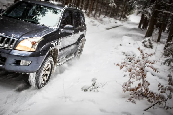 雪に覆われた森林の道を速く行く大きなSuv車の動きのぼやけたイメージ — ストック写真