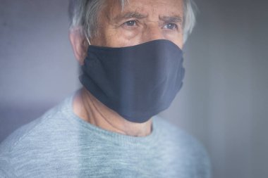 Koronavirüs ve grip salgını sırasında maske takan kıdemli bir adam. Virüs ve hastalık koruması, ev karantinası. COVID-19 kavramı