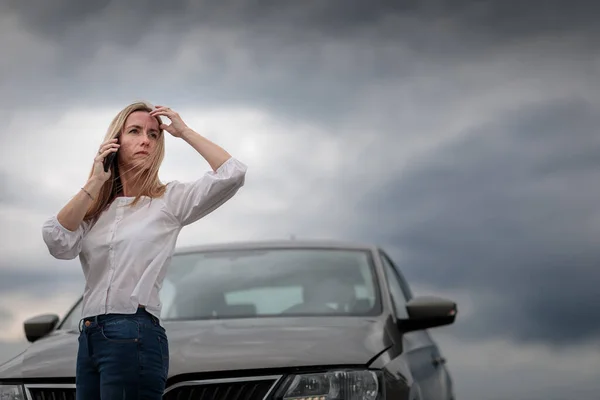 車のトラブルを抱えているかなり中年の女性 道路の側に車を故障させ 支援のために保険会社を呼び出す — ストック写真