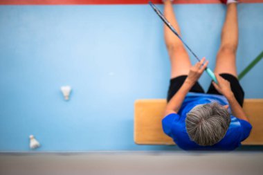 Badminton oyuncusu, kapalı bir salonda oynanan sert bir maçtan sonra dinleniyor.