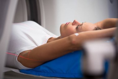 Modern bir hastanede Bilgisayarlı Eksen Tomografisi (CAT) taraması yapan güzel, genç bir kadın (renk tonlu görüntü; sığ DOF)