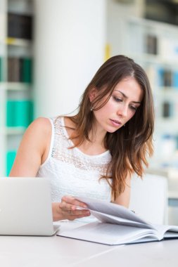 Kütüphanedeki güzel genç üniversite öğrencisi (sığ DOF; renk tonlu resim)