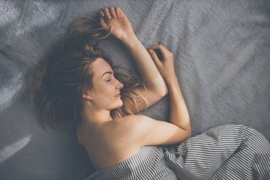 Güzel, genç bir kadın hafta sonu geç saatlere kadar yatağında uyuyor. Uykusuzluğunu telafi ediyor.