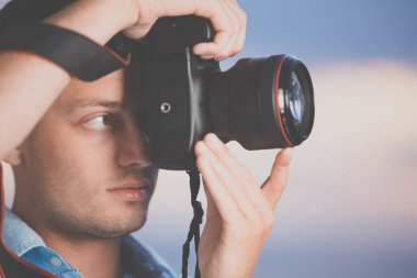 Yakışıklı genç fotoğrafçı modern DSLR açık hava, sevimli gökyüzü arkaplan karşı (renk tonlu görüntü; sığ DOF;)