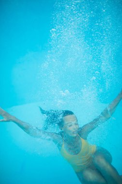 Havuzda güzel bir genç kadın, atlıyor ve suya dalıyor, eğleniyor.