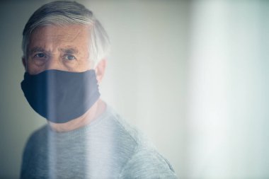 Koronavirüs ve grip salgını sırasında maske takan kıdemli bir adam. Virüs ve hastalık koruması, ev karantinası. COVID-19 kavramı