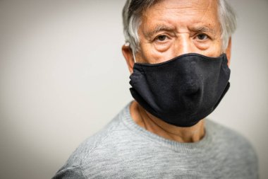Koronavirüs ve grip salgını sırasında maske takan kıdemli bir adam. Virüs ve hastalık koruması, ev karantinası. COVID-19 kavramı