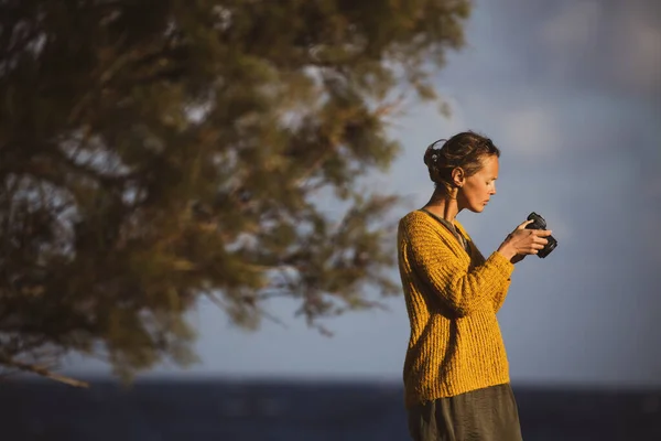 漂亮的年轻女子带着无镜相机在海边拍照 — 图库照片