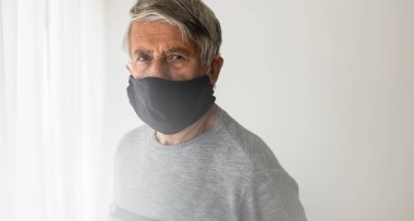 Koronavirüs ve grip salgını sırasında maske takan kıdemli bir adam. Virüs ve hastalık koruması, ev karantinası. COVID-19 kavramı