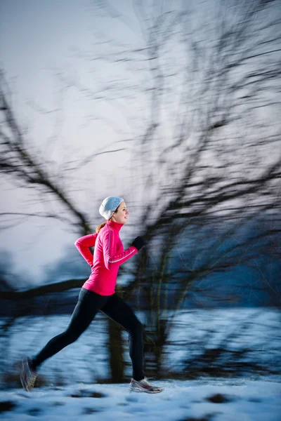 Молодая женщина, бегущая на улице в холодный зимний день — стоковое фото