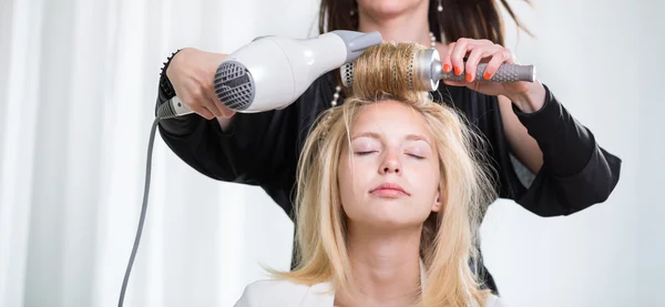 Hairstyle artist working on a young woman's hair — Stock Photo, Image