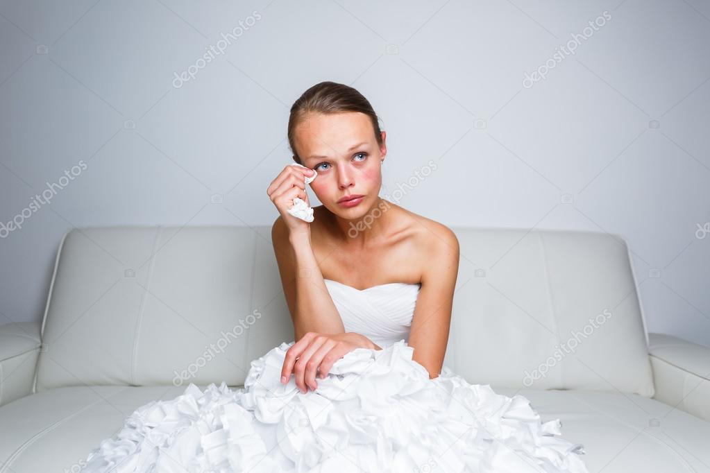 Sad bride crying sitting on a sofa