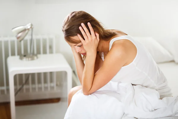 Mulher sentada na cama parecendo infeliz, deprimida — Fotografia de Stock