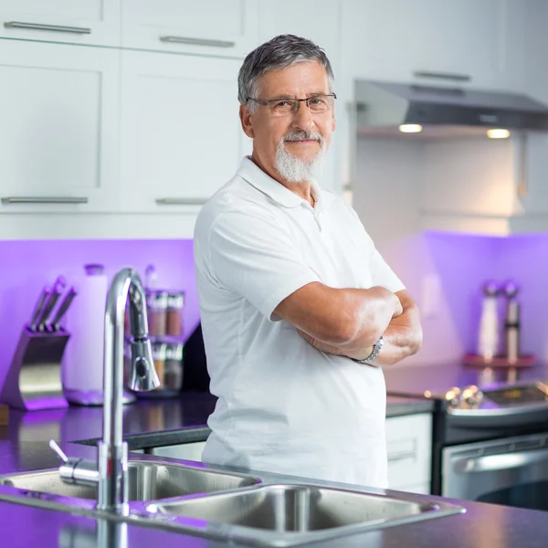 Starší muž, stojící v jeho moderní kuchyni — Stock fotografie