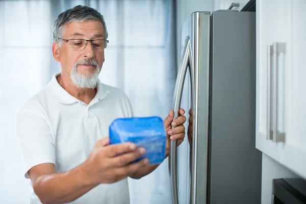 Homem sênior em sua cozinha perto da geladeira — Fotografia de Stock