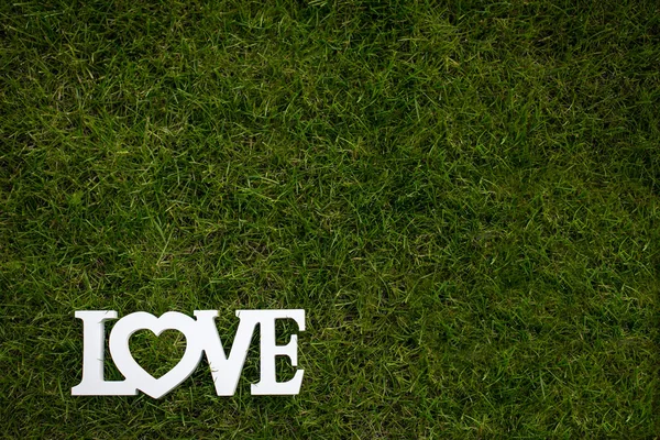 Word LOVE couché dans l'herbe luxuriante et bien coupée — Photo