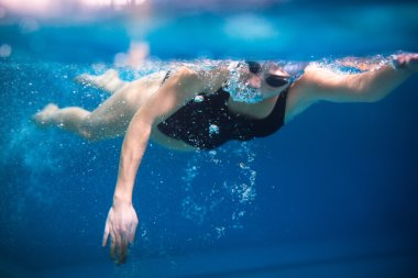 Bir kapalı yüzme havuzunda kadın yüzücü