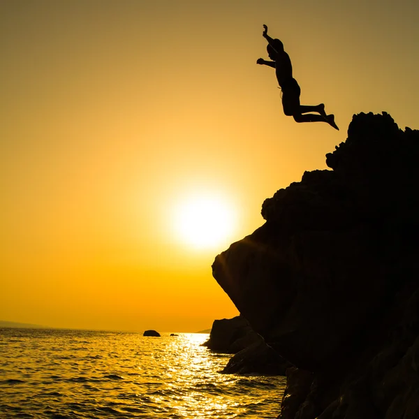 Rapaz silhueta saltando para o mar — Fotografia de Stock