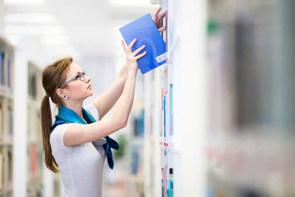 Female college student in a library, looking for a book — Stock Photo, Image