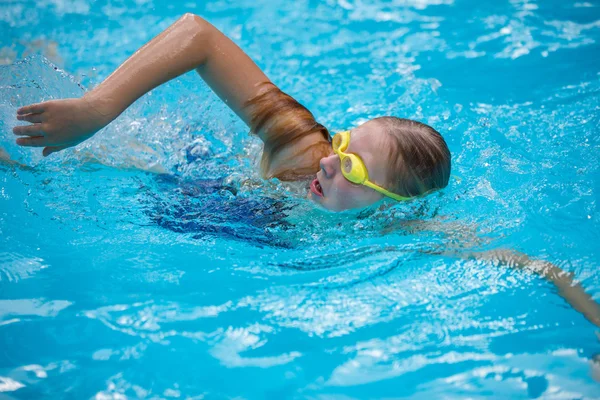Young girl in goggles and cap swimming crawl stroke style — Stock Photo, Image