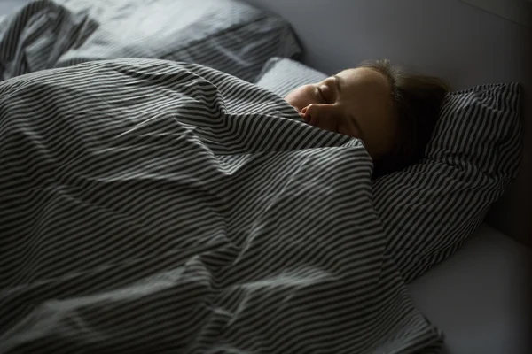 Ung kvinna sover i sängen — Stockfoto