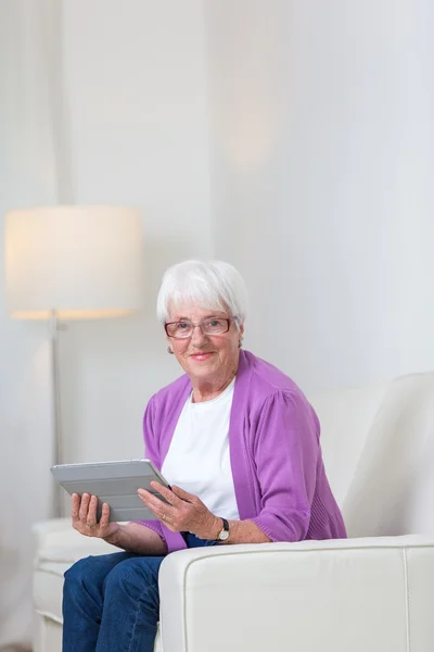 Пожилая женщина дома с помощью планшетного компьютера — стоковое фото