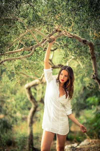 Jonge brunette op het strand, te midden van olijfbomen — Stockfoto