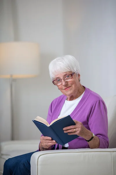Портрет пожилой женщины дома - Выглядит счастливой, глядя на футболку — стоковое фото