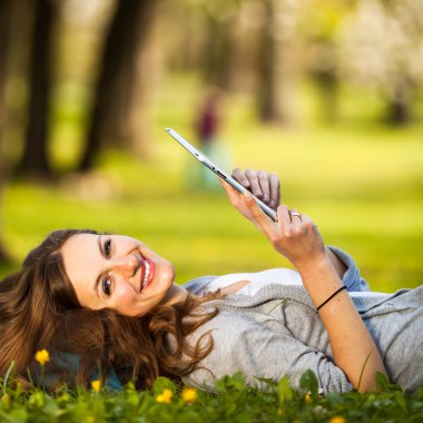 açık havada dinlenirken tablet bilgisayarını kullanan genç kadın