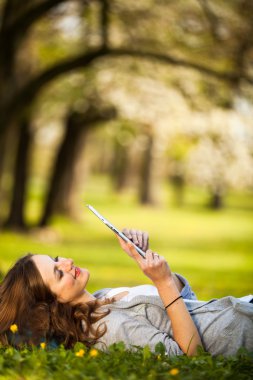 açık havada dinlenirken tablet bilgisayarını kullanan genç kadın