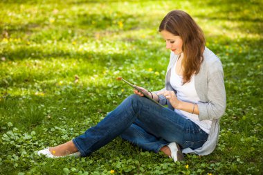 açık havada dinlenirken tablet bilgisayarını kullanan genç kadın