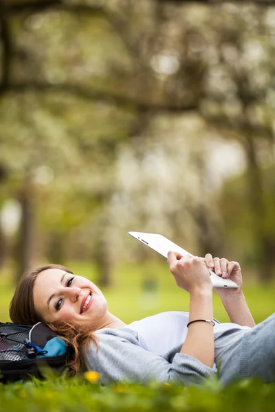 Young woman using her tablet computer while relaxing outdoors — Stock Photo, Image