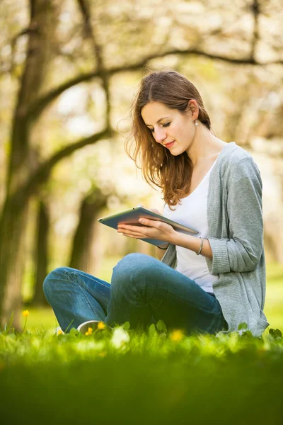 Jovem mulher usando seu computador tablet enquanto relaxa ao ar livre — Fotografia de Stock