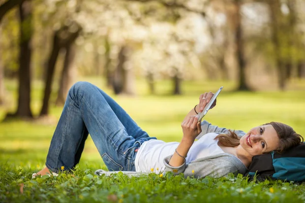 Young woman using her tablet computer while relaxing outdoors — Stock Photo, Image