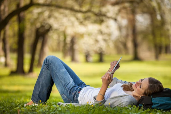 Açık havada dinlenirken tablet bilgisayarını kullanan genç kadın — Stok fotoğraf