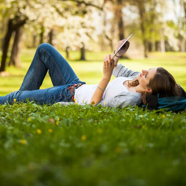 Jonge vrouw met behulp van haar tablet-pc terwijl u ontspant buitenshuis — Stockfoto