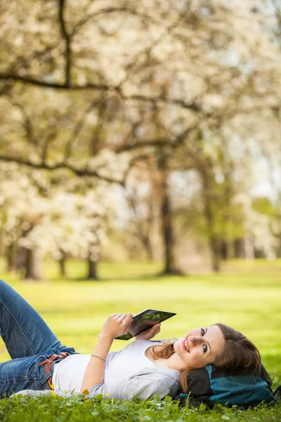 Young woman using her tablet computer while relaxing outdoors — Stock Photo, Image