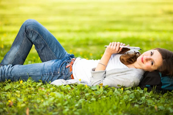 Mujer joven usando su tableta mientras se relaja al aire libre —  Fotos de Stock
