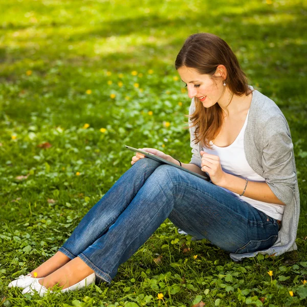 Young woman using her tablet computer while relaxing outdoors — Stock Photo, Image